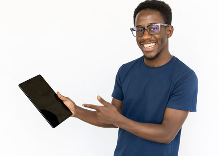 Positive man pointing at tablet. Young African American male model holding tablet and showing something on it. Portrait, studio shot, technology, advertising conceptの写真素材
