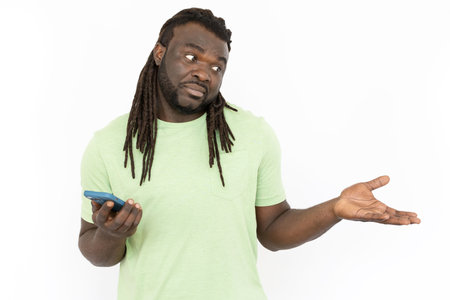 African American man with phone in hands making helpless gesture. Man having no idea how to solve problem, shrugging his shoulders. Confusion, doubt, wonder conceptの写真素材