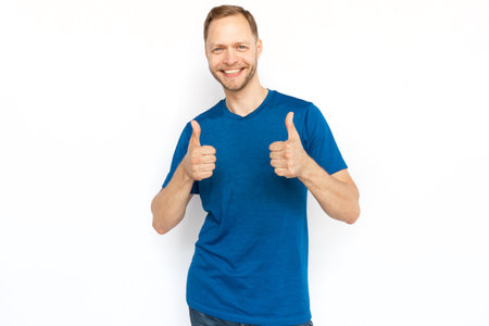 Happy Caucasian man smiling and showing thumbs up gestures. Cheerful bearded man standing on white background, rejoicing and showing approving gestures. Agreement, approval, happiness conceptの写真素材