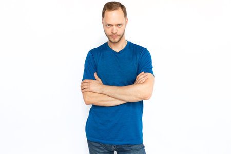 Serious man standing with folded arms and looking at camera. Bearded Caucasian man posing for camera while standing on white background. Confidence, self-assurance conceptの写真素材