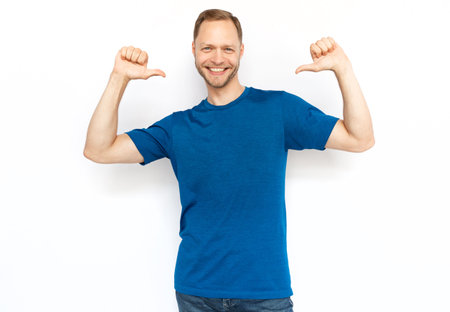 Caucasian man pointing with thumbs at himself. Proud bearded man looking at camera, smiling, standing on white background, choosing himself. Self-assurance, confidence conceptの写真素材