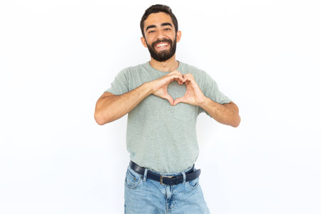 Joyful man showing heart with hands. Young male model making heart symbol, pressing hands to chest. Portrait, studio shot, love conceptの写真素材
