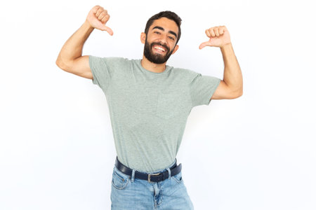 Proud man pointing at himself with thumbs. Young male model celebrating victory. Portrait, studio shot, success conceptの写真素材