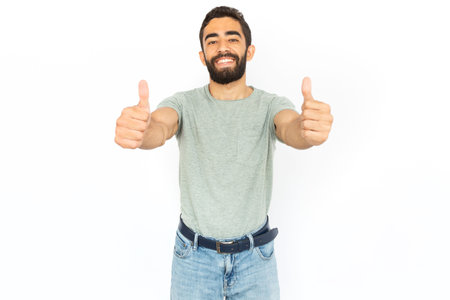 Cheerful man showing thumbs up. Young male model making like gesture and smiling. Portrait, studio shot, support conceptの写真素材