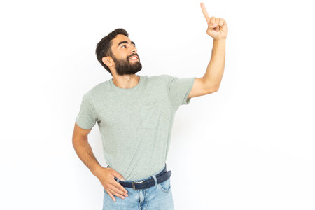 Happy man pointing up. Young male model looking up showing something. Portrait, studio shot, advertising conceptの写真素材