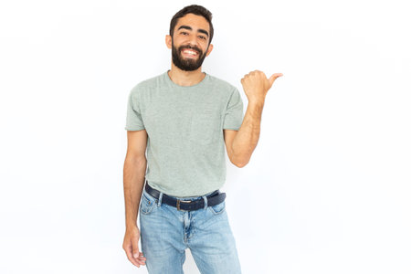 Happy man showing something with thumb. Young male model pointing at something with thumb. Portrait, studio shot, advertising conceptの写真素材