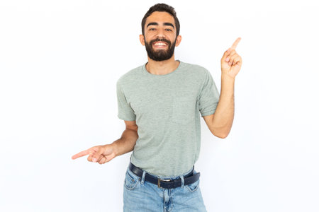 Joyful man dancing. Young male model celebrating success or pointing at two different spots. Portrait, studio shot, success, advertising conceptの写真素材