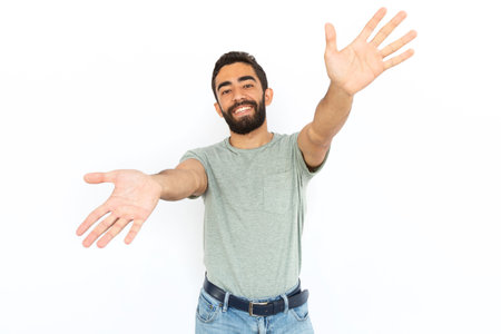 Joyful man reaching out to camera. Young male model stretching arms before embracing someone or presenting something. Portrait, studio shot, support, advertising conceptの写真素材