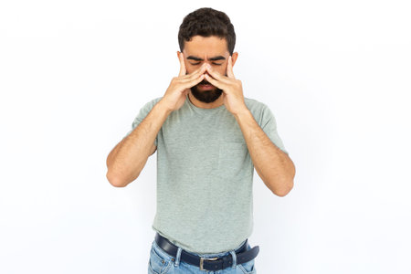 Tired man rubbing nose. Young male model experiencing stress or pain. Portrait, studio shot, stress, health conceptの写真素材