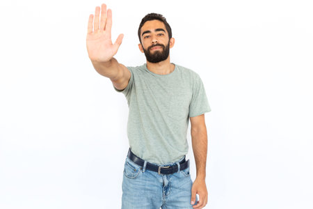 Serious man showing stop gesture. Young male model stopping somebody, prohibiting something. Portrait, studio shot, prohibition conceptの写真素材