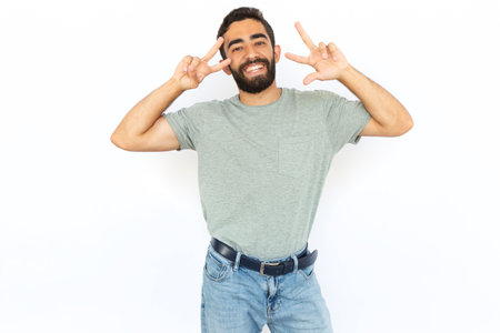 Joyful man making victory gesture. Young male model showing peace sign with both hands. Portrait, studio shot, success, peace conceptの写真素材