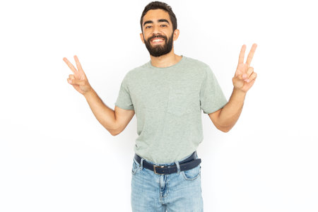 Happy man showing peace sign. Young male model smiling and making victory gesture with both hands. Portrait, studio shot, happiness, victory conceptの写真素材