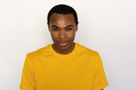 Portrait of confident young man looking at camera. African American guy wearing yellow T-shirt posing against white background. Confidence conceptの写真素材