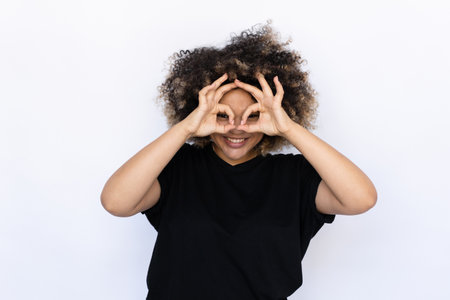 Funny woman making glasses with fingers. Young female model looking through glasses or mask made...