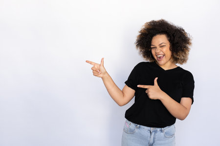 Joyful woman pointing aside. Young female model presenting something with excitement. Portrait, studio shot, advertising conceptの写真素材