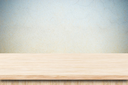 Empty wooden table over grunge cement wall.