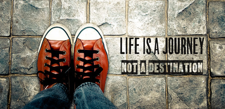 Feet in leather sneaker on pavement background, top viewの写真素材