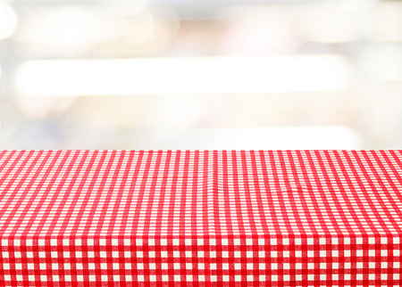 Empty table with red check tablecloth over blur festive bokeh background, product displayの写真素材