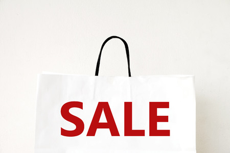 Sale word on white shopping bag over white wall background, discount, marketing, business