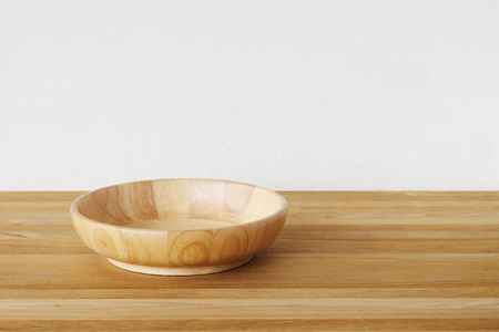 Empty round wooden plate on wood table and cement wall background, food display montageの写真素材