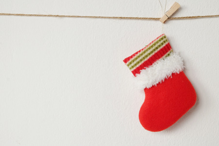 Red Christmas sock hanging on white wall background with copy space