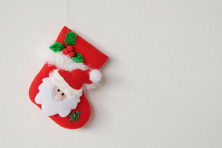 Red Christmas sock hanging on white wall background with copy spaceの写真素材