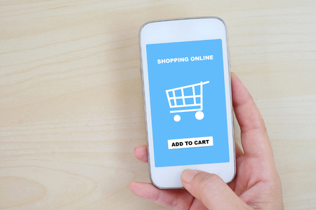 Hand  holding smart phone with shopping on line on screen, omnichannel, business and technology conceptの写真素材
