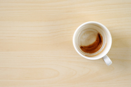 Coffee stain in cup on wood background, with copy space