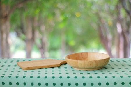 Empty wooden tray and blow on table with green polka dot tablecloth over blur tree background , food display montageの写真素材