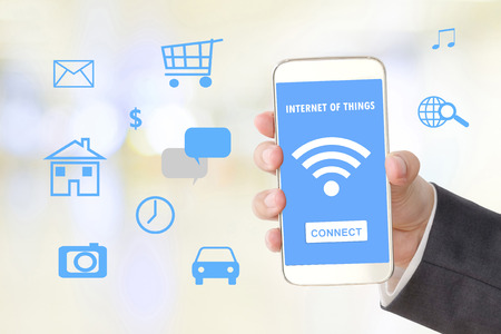 Businessman hand holding smart phone and internet of things icons, business and technology conceptの写真素材