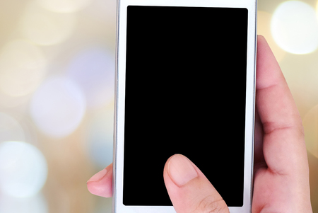 Hand holding smart phone over blur bokeh background, e-commerce, smart pay, business and technology conceptの写真素材