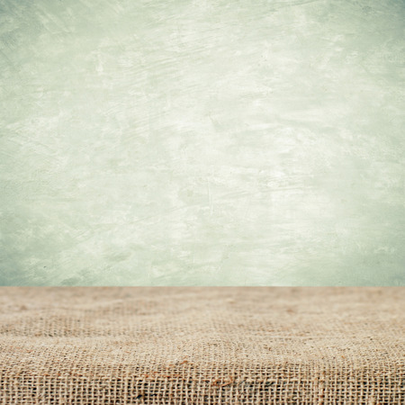 Empty table and sack tablecloth over grunge cement wall background, product display montage, vintage styleの写真素材
