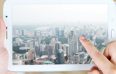 Hand pointing wifi icon over blur city background on tablet screen, internet of thing conceptの写真素材