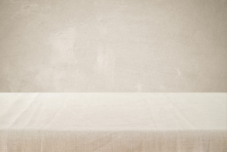 Empty table with linen tablecloth over brown cement wall background, product display montage