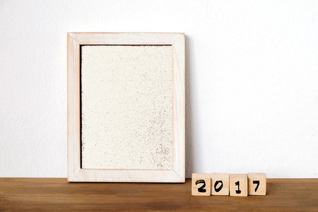 2017 on wood cubes and blank vintage white frame on table background, template, new year conceptの写真素材