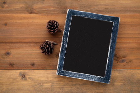 Blank black wooden frame and pine cones on vintage wood background, templateの写真素材