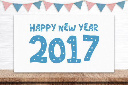 Happy new year 2017 on white board and party flags hanging on white wood background