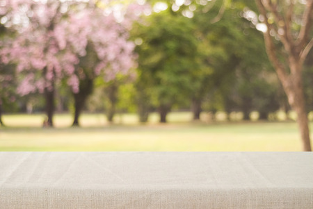 Empty table with linen tablecloth over blur park with bokeh background, food and product display montageの写真素材