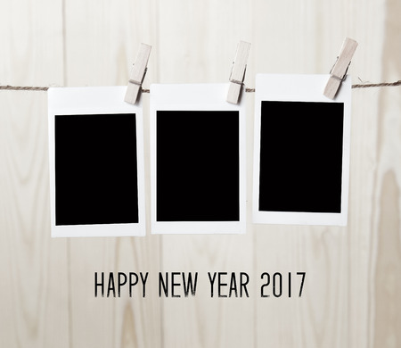 Three instant photo frames hanging on wood background with happy new year 2017 word, templateの写真素材