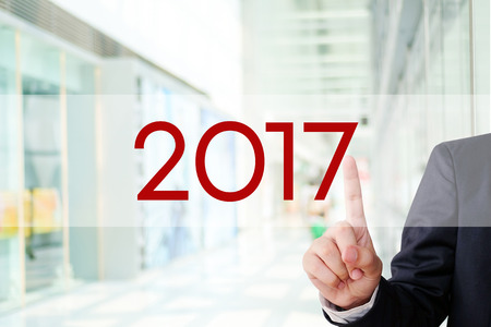 Businessman hand touch 2017 button over blur office background, new year business conceptの写真素材