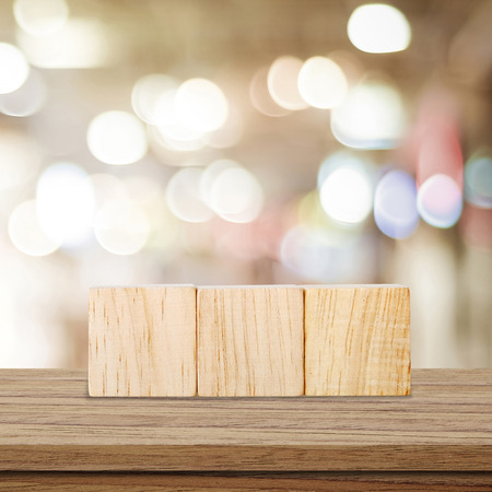 Three wooden cubes on table over blur abtract bokeh light backgroundの写真素材