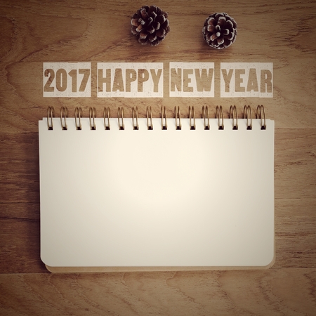 2017 happy new year words and blank note book paper on wood background, space for textの写真素材