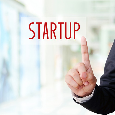 Businessman hand point start up word on blur background, success in business concept