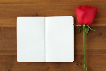 Red rose and blank note book paper on wood background, valentine's day conceptの写真素材