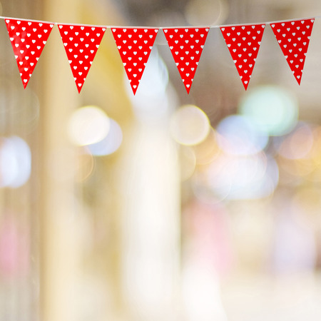 Red bunting party flag with heart shape pattern on blur abstract bokeh light background, with copy space for text, valentine's day conceptの写真素材