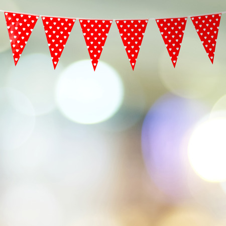 Red bunting party flag with heart shape pattern on blur abstract bokeh light background, with copy space for text, valentine's day conceptの写真素材