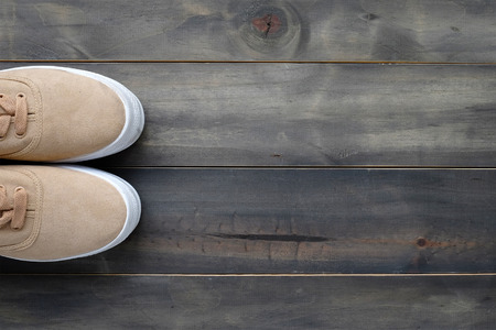 Brown leather sneakers on vintage wood background, top view with copy space for text and product...