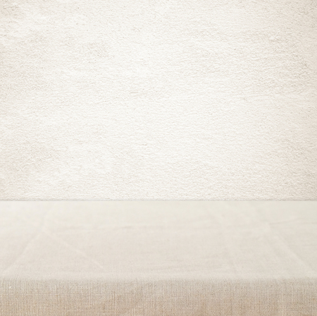Empty table with linen tablecloth over vintage cement wall background, product display montageの写真素材
