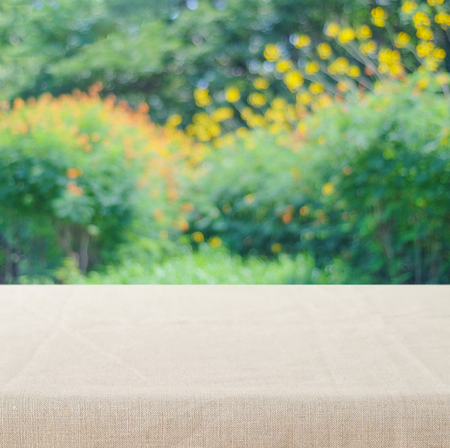 Empty table with linen tablecloth over blur park with bokeh background, food and product display montageの写真素材