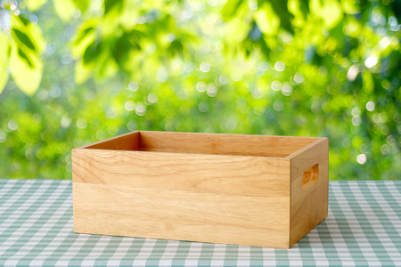 Empty wooden box on table with green scott pattern tablecloth over blur tree with bokeh light background, product display montageの写真素材